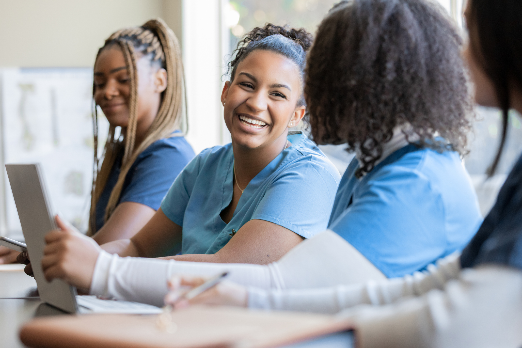 Happy young adult nursing or medical student talks with classmate in university medical training class